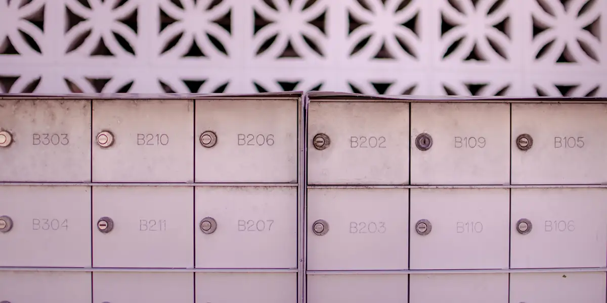 Două blocuri de cutii poștale metalice deschise la culoare, cu numerele B303, B210, B206, B202, B109, B105 pe rândul de sus și B304, B211, B207, B203, B110, B106 dedesubt