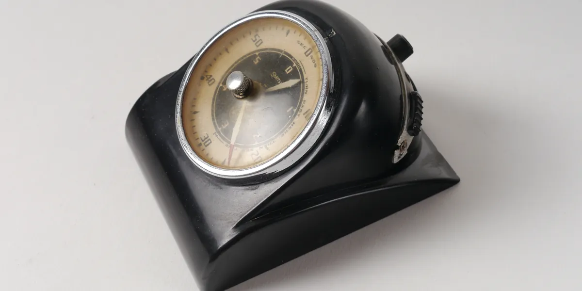 A black bakelite desk instrument with a chrome-rimmed circular dial, needle near zero, small numbers around the face, photographed on a plain light background