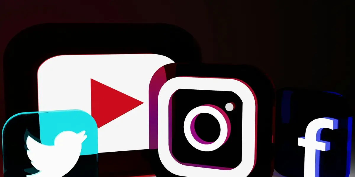 Pictograme tridimensionale ale aplicațiilor sociale — Twitter, YouTube, Instagram și Facebook — așezate una lângă alta pe fundal închis